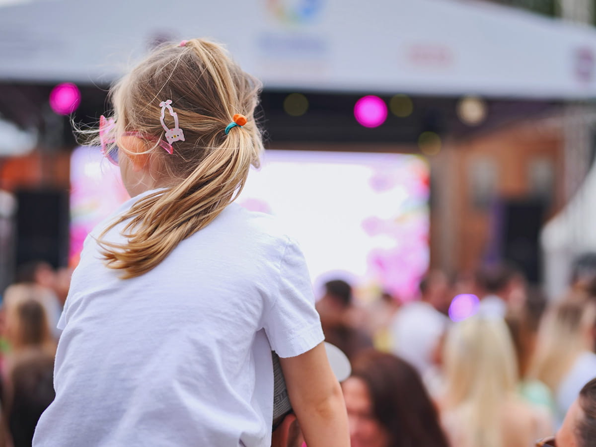 Une jeune fille, observe la foule d'un festival en plein air